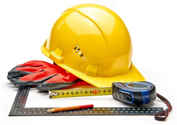 A hard hat gloves tape measure ruler and pencil on a white background