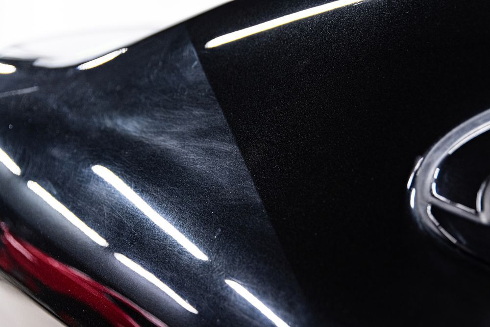Black car surface, one side polished, the other with swirls and scratches.
