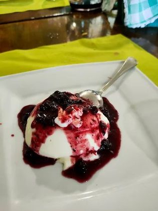 Un piatto bianco con gelato e salsa ai frutti di bosco con un cucchiaio