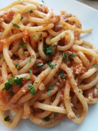 Un primo piano di un piatto di pasta con salsa e prezzemolo