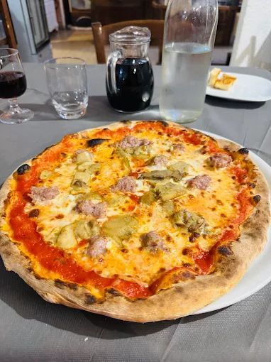 Una pizza è appoggiata su un piatto bianco su un tavolo.