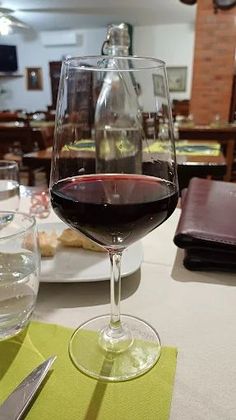 Un bicchiere di vino rosso è appoggiato su un tavolo in un ristorante.