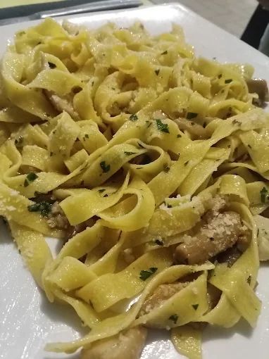 Un primo piano di un piatto di pasta con funghi su un tavolo.