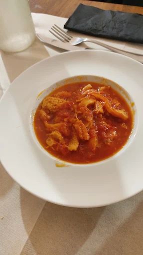 Un piatto bianco sormontato da una ciotola di zuppa su un tavolo.