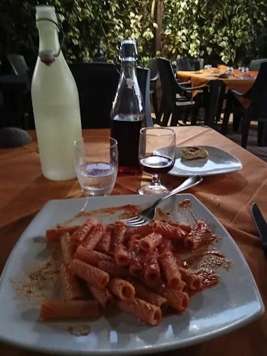 Un piatto di pasta è appoggiato su un tavolo accanto a una bottiglia d'acqua