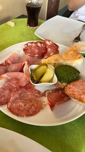 Un piatto bianco con sopra carne e pane su un tavolo.