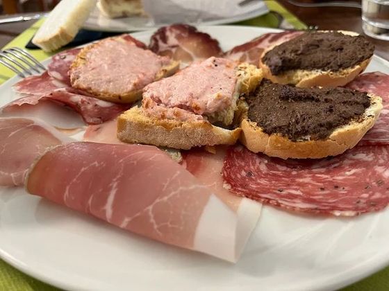 Un piatto bianco con sopra carne e pane su un tavolo.