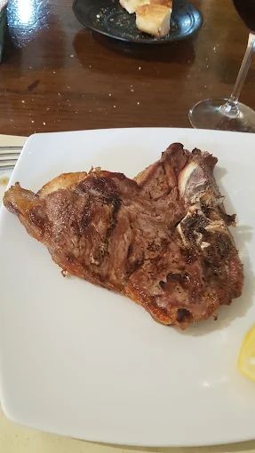Un pezzo di carne è su un piatto bianco su un tavolo.