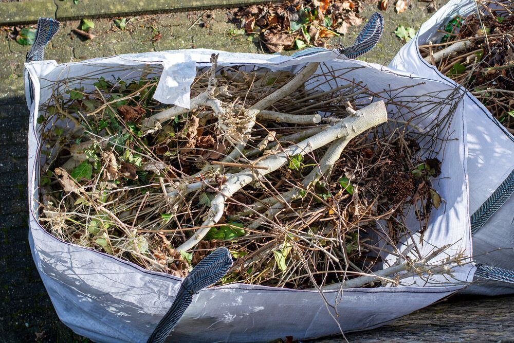 A Green Trash Can Filled With Grass Is Sitting On The Ground — Mackay Bags in East Mackay, QLD
