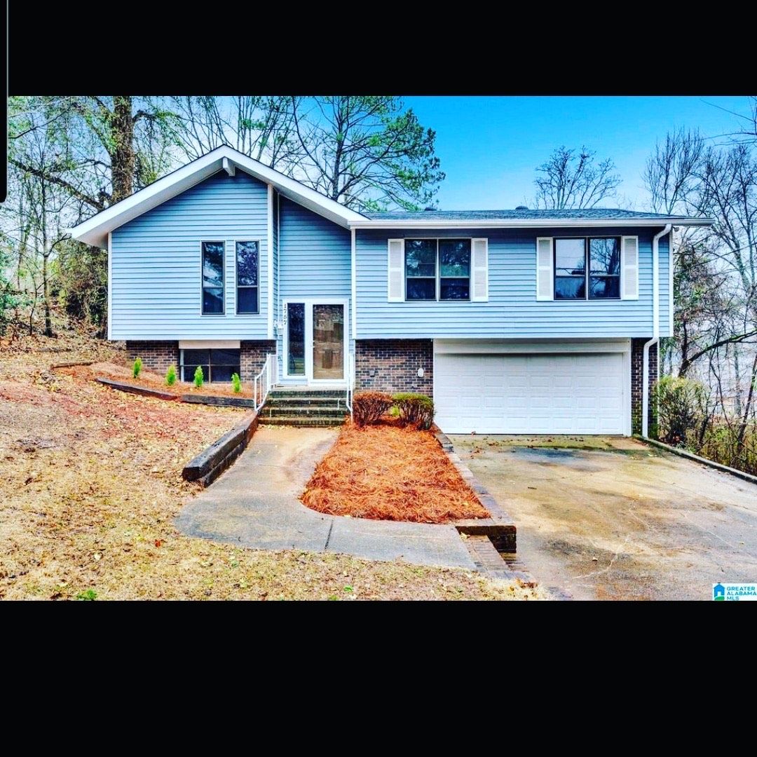 A blue house with a white garage door is sitting on top of a hill.