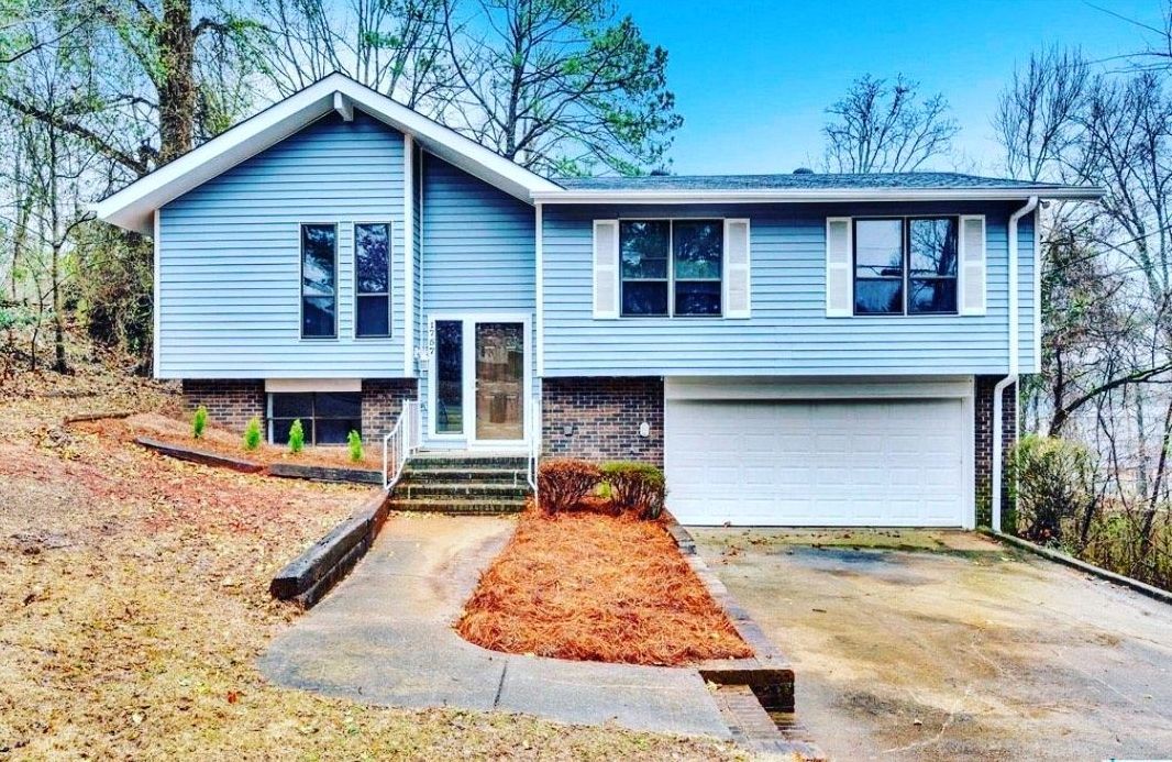 A blue house with a white garage door is sitting on top of a hill.