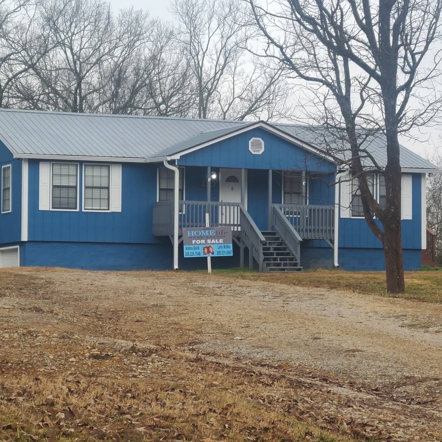 A blue house with a for sale sign in front of it