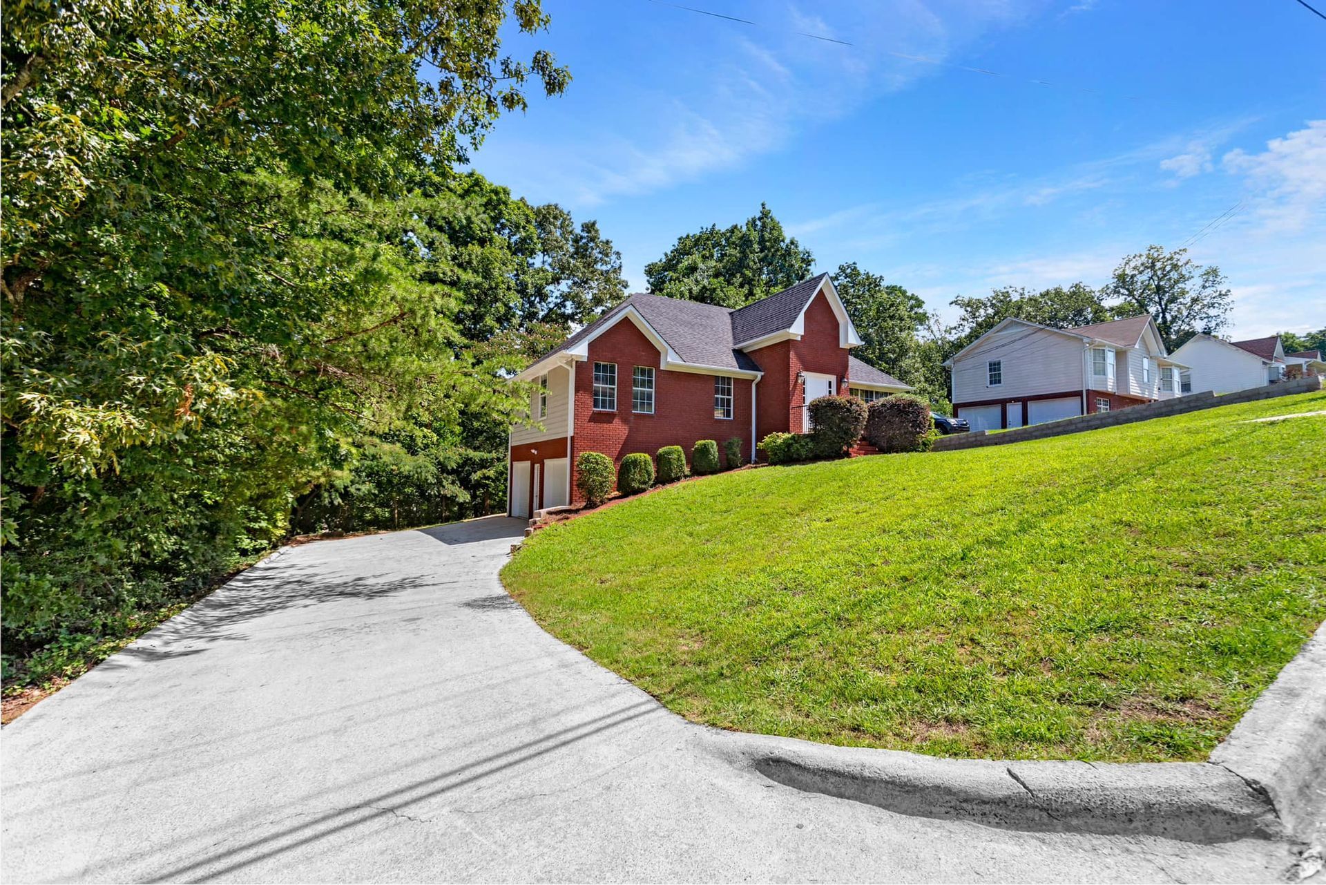 A red house is sitting on top of a lush green hill.