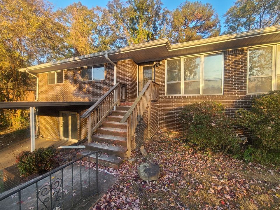 A brick house with stairs leading up to the front door and a deck.