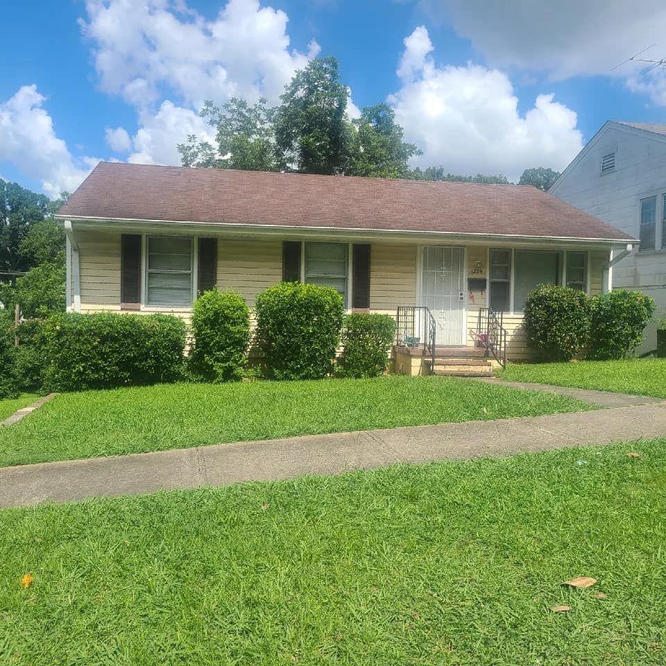 A house with a brown roof and a lush green lawn