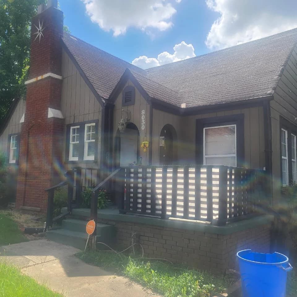 A house with a brick chimney and a porch on a sunny day.