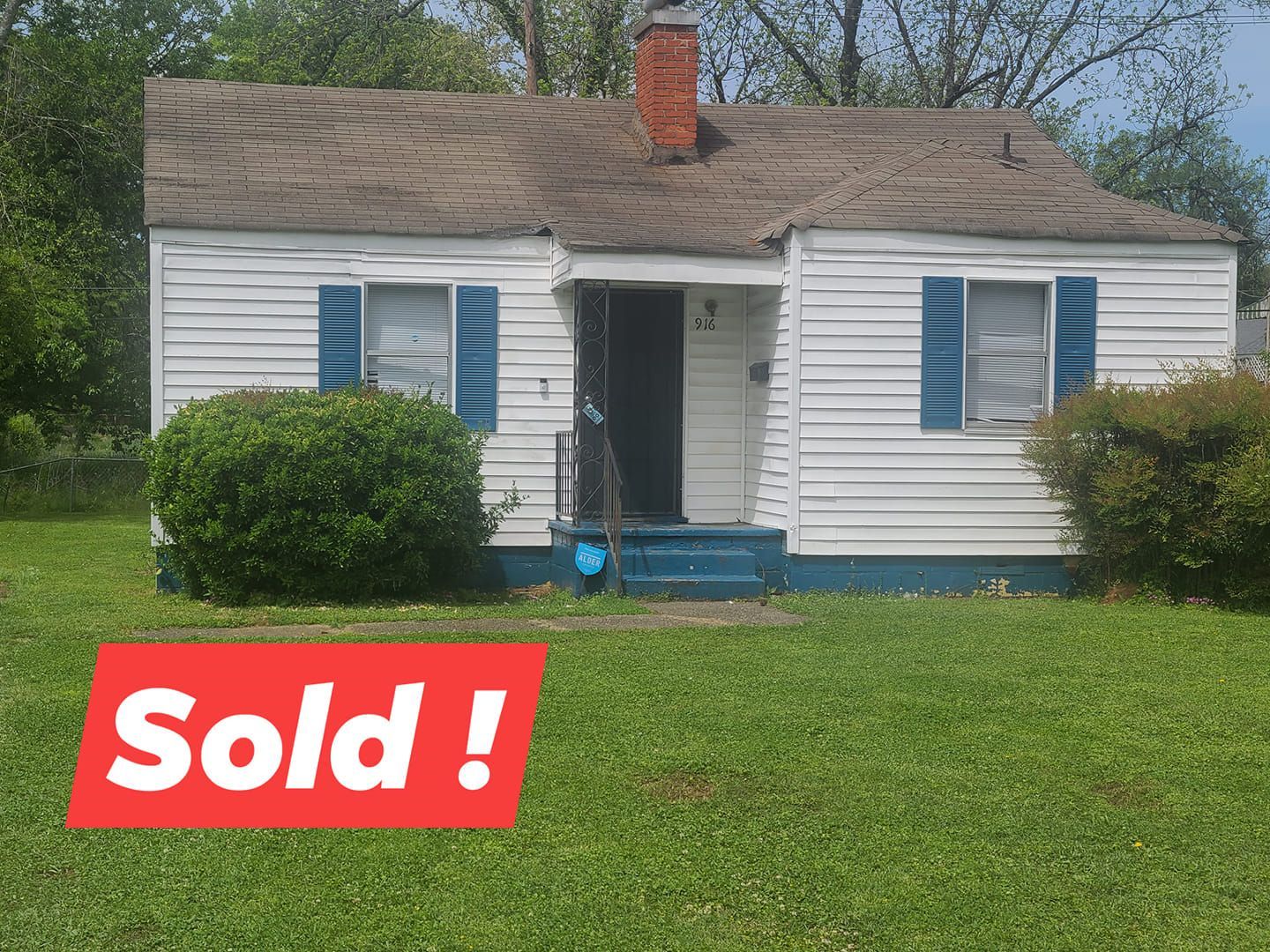 A small white house with blue shutters is for sale.