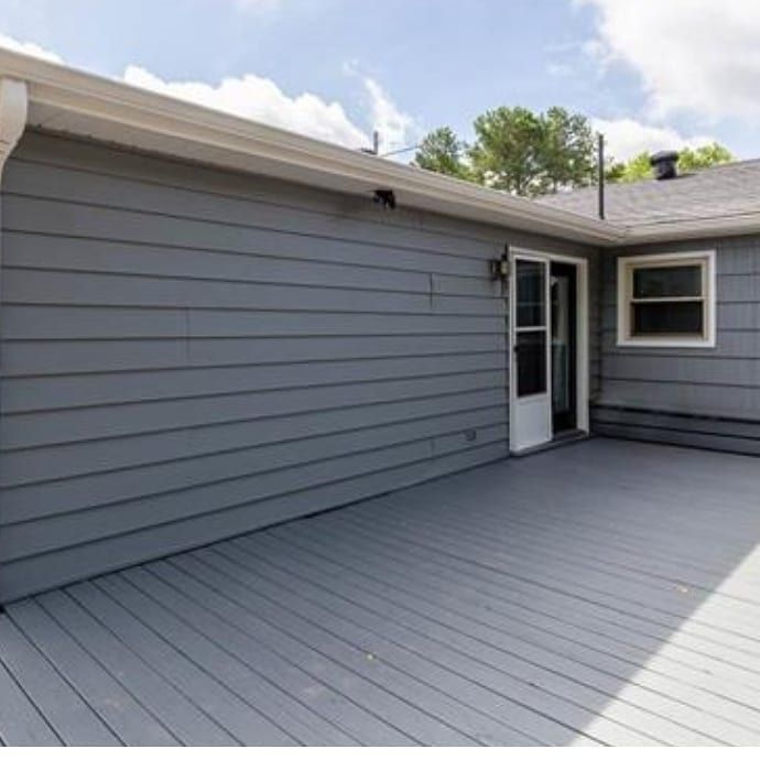 A gray house with a large deck in front of it