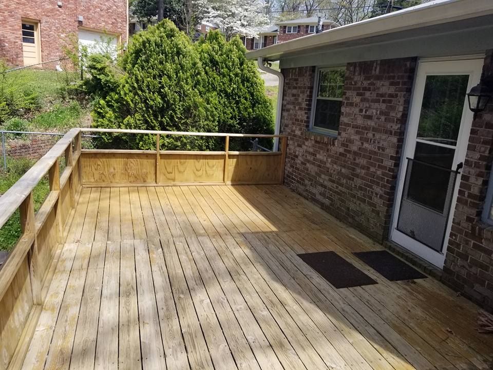 A wooden deck is sitting in front of a brick house.