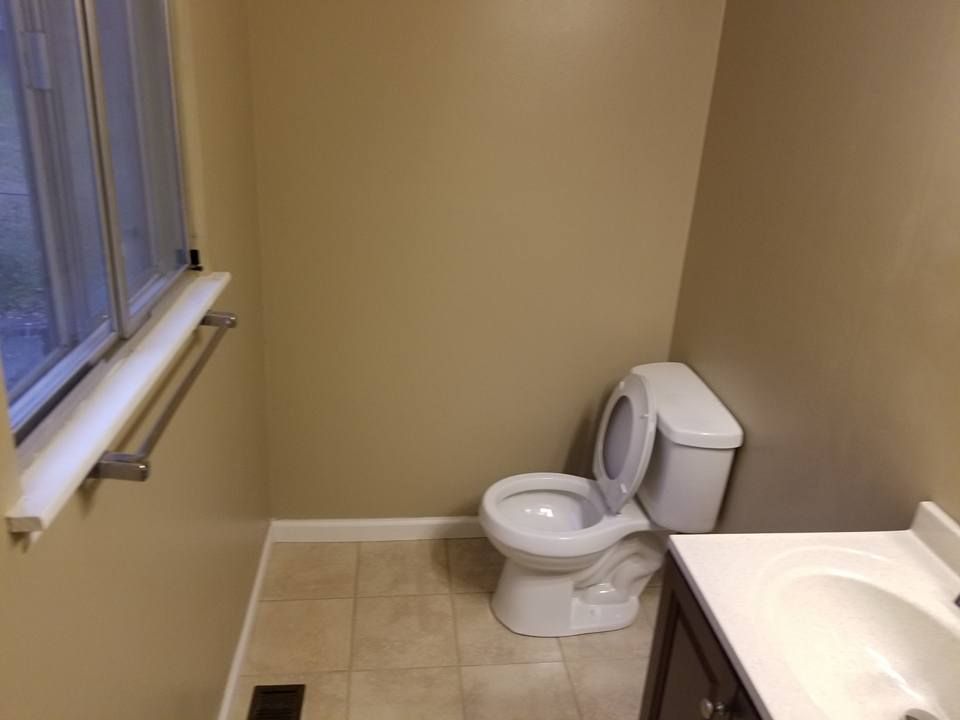 A bathroom with a toilet , sink and window.