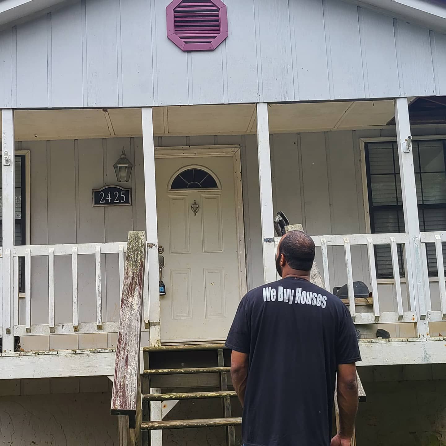 A man wearing a black shirt that says we buy homes