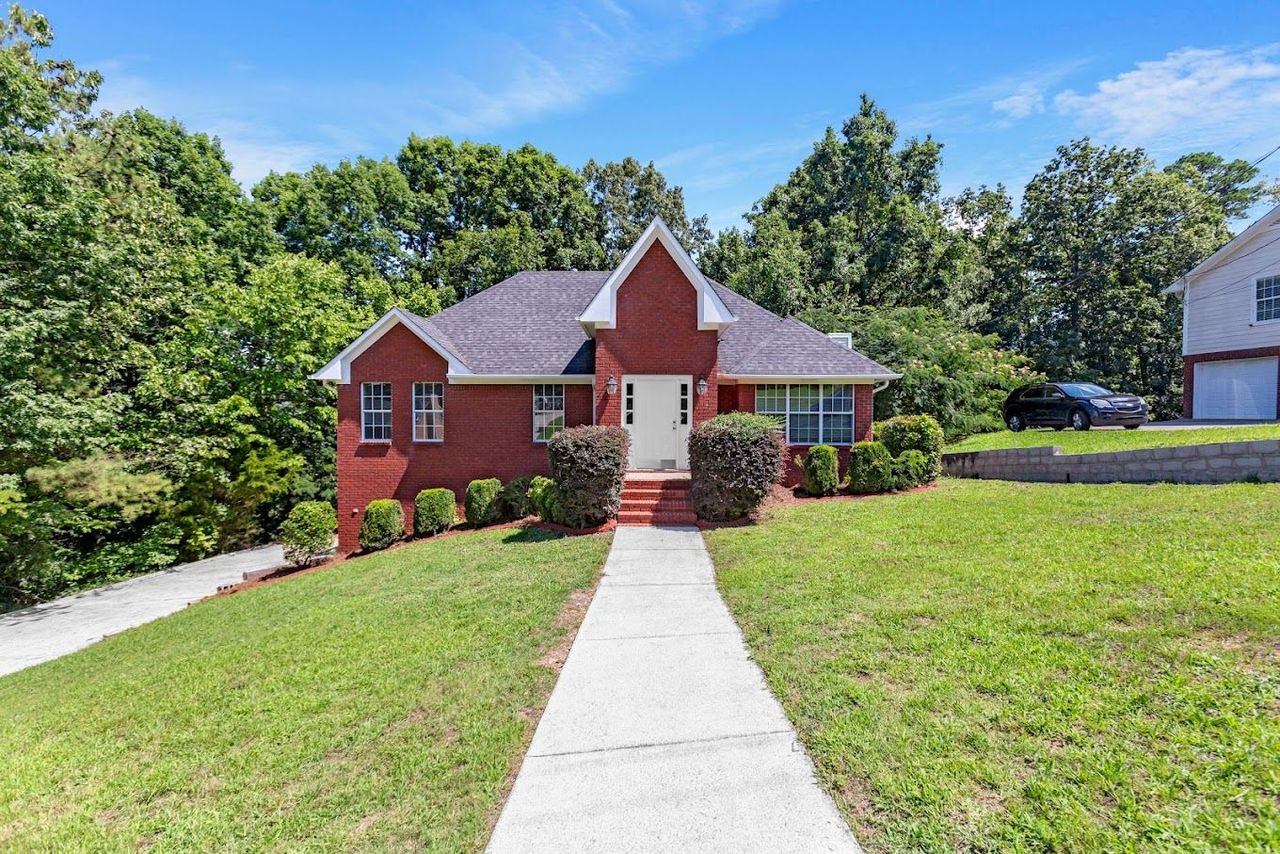 A red brick house with a concrete walkway leading to it.