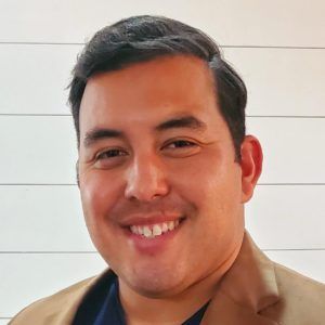 Joshua Rodriguez A man in a suit and blue shirt is smiling for the camera.