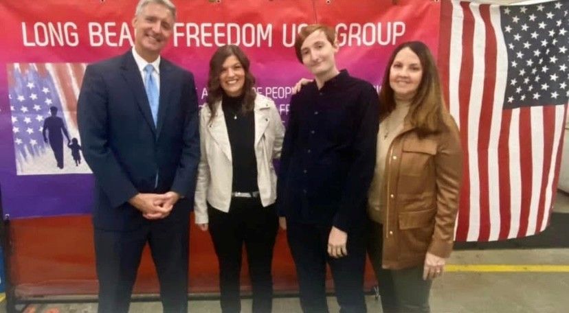 Four people stand in front of a banner that reads