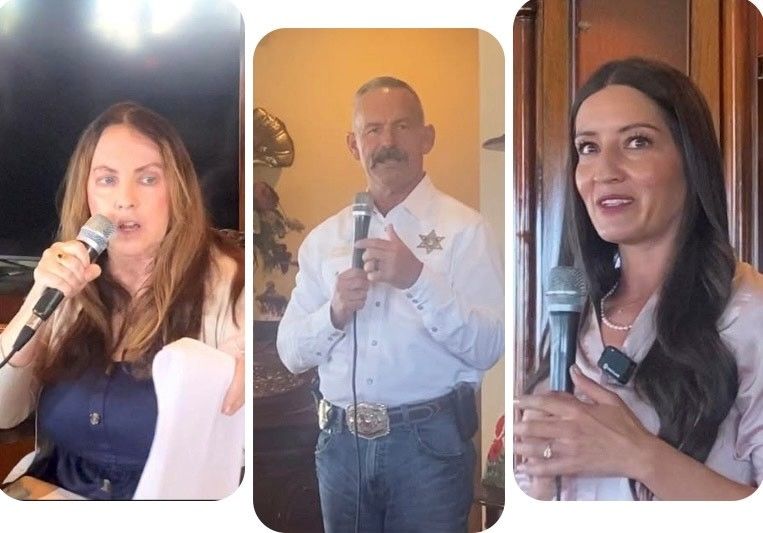 Three people speaking into microphones: a woman at left, a man in the center wearing a sheriff's badge, and a woman at right.