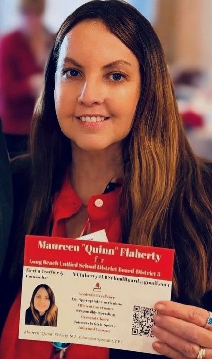 Woman holding a red flyer with her portrait and text, smiling at the camera.