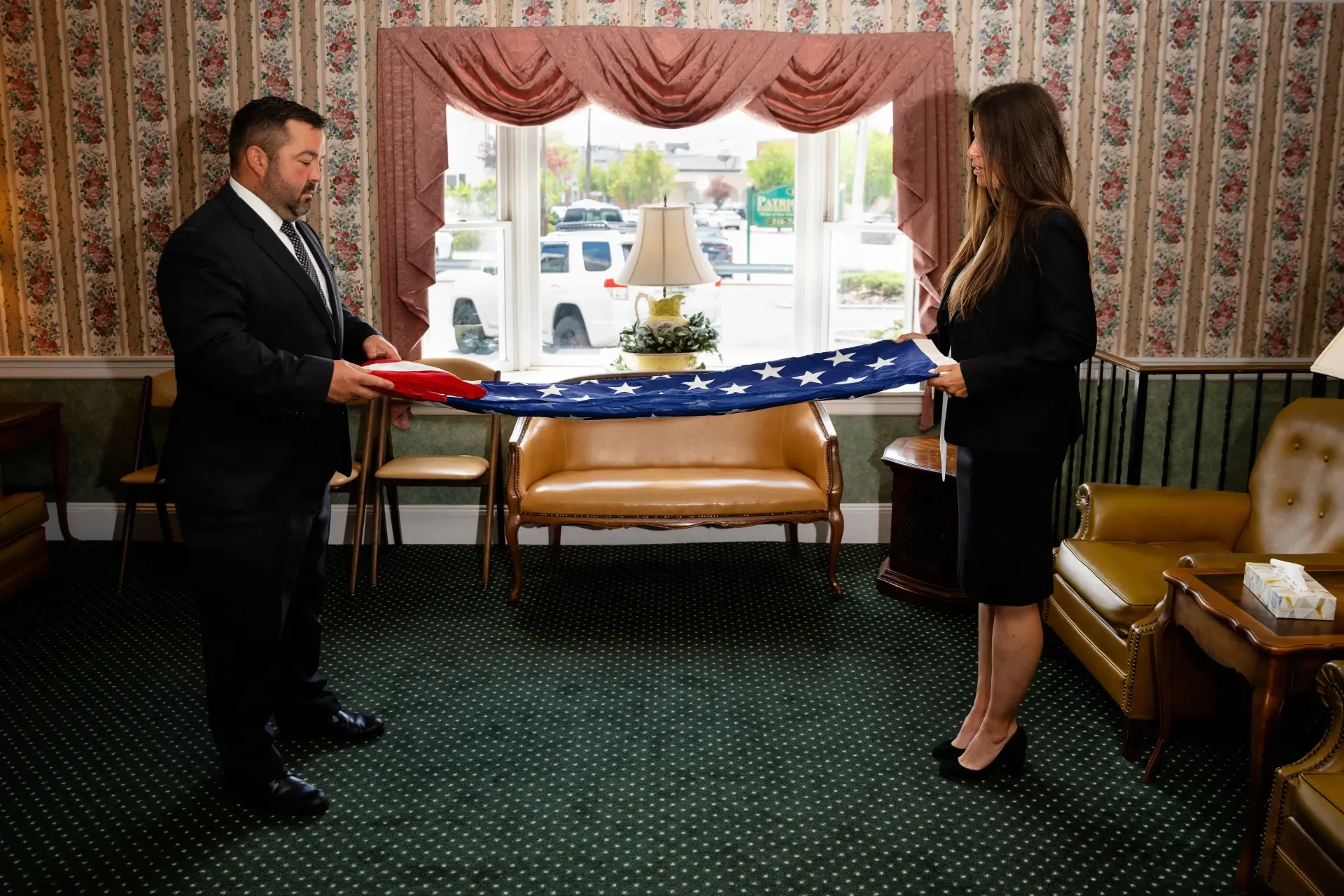 A person is putting their hand on an american flag at a funeral.