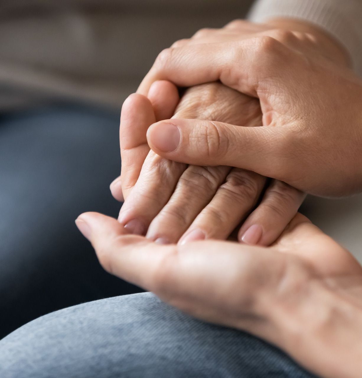 A woman is holding the hands of an older woman.