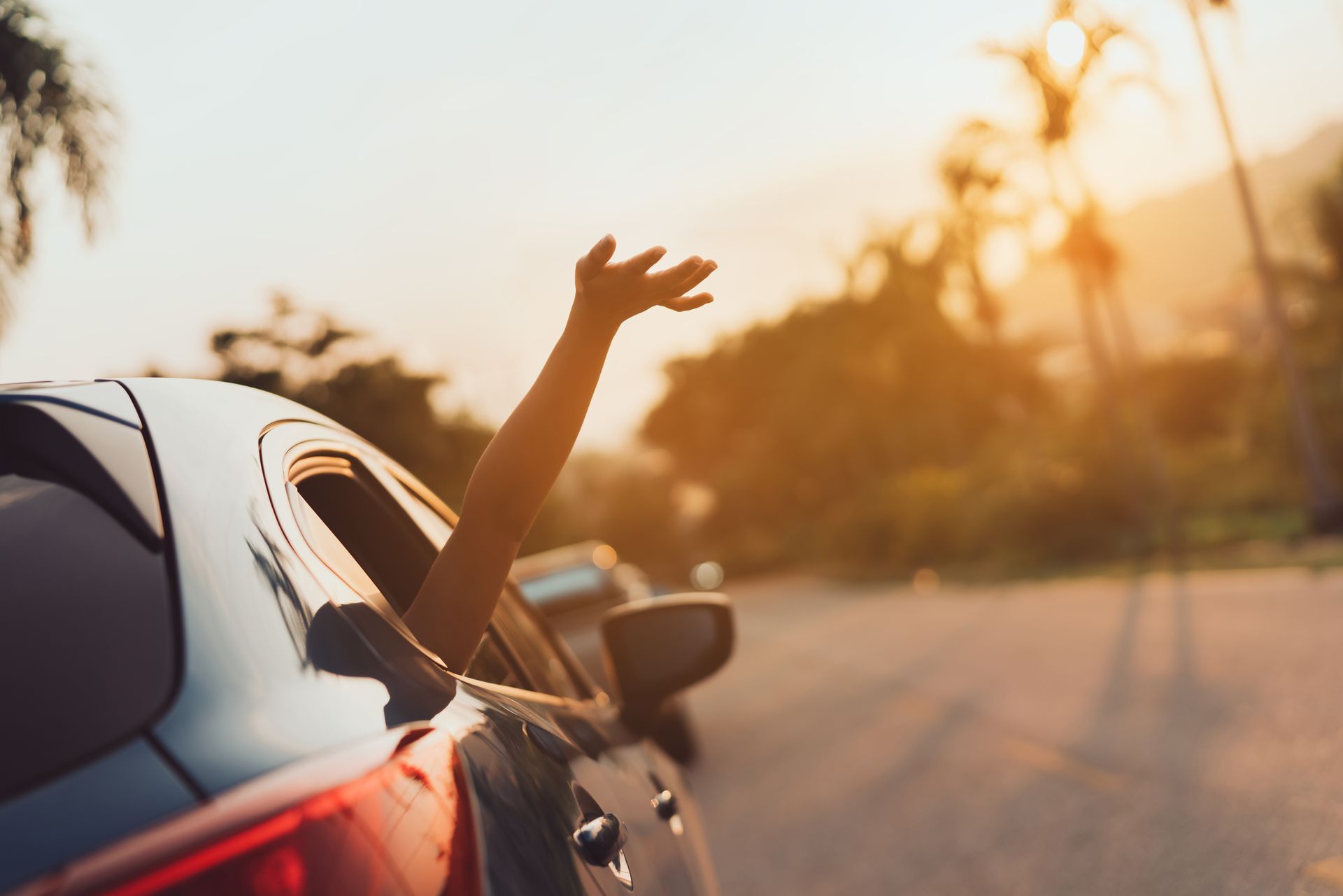 A person's arm raised out of a car window, enjoying the sunlight    