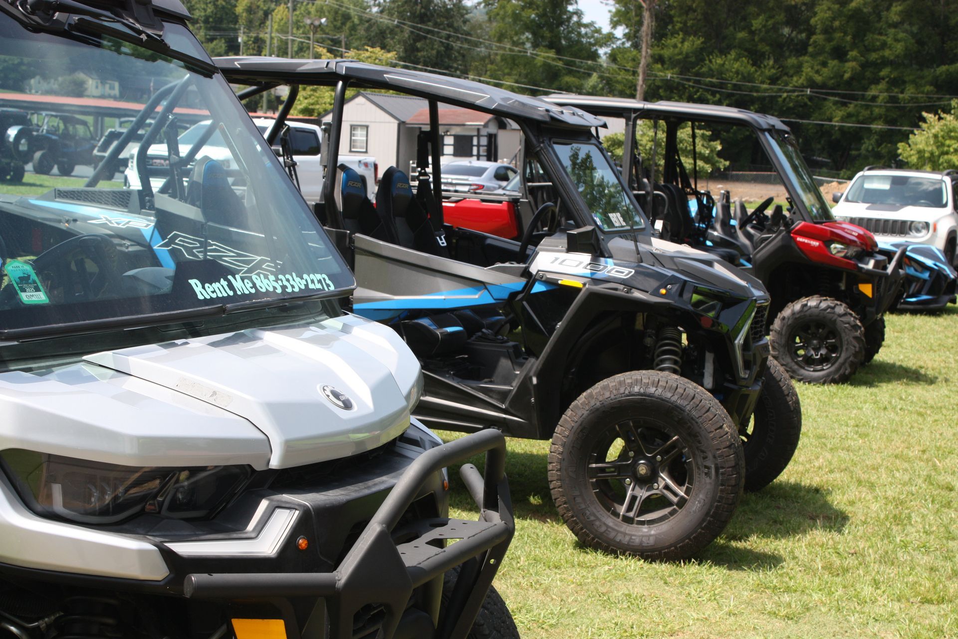 A row of atvs are parked in a grassy field.