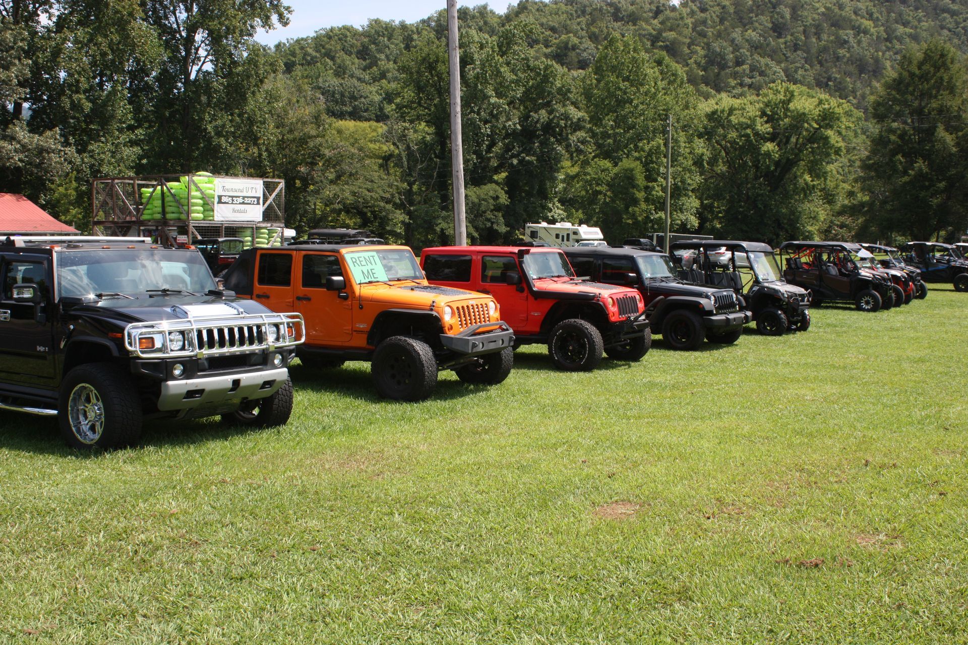 A row of jeep 's are parked in a grassy field.