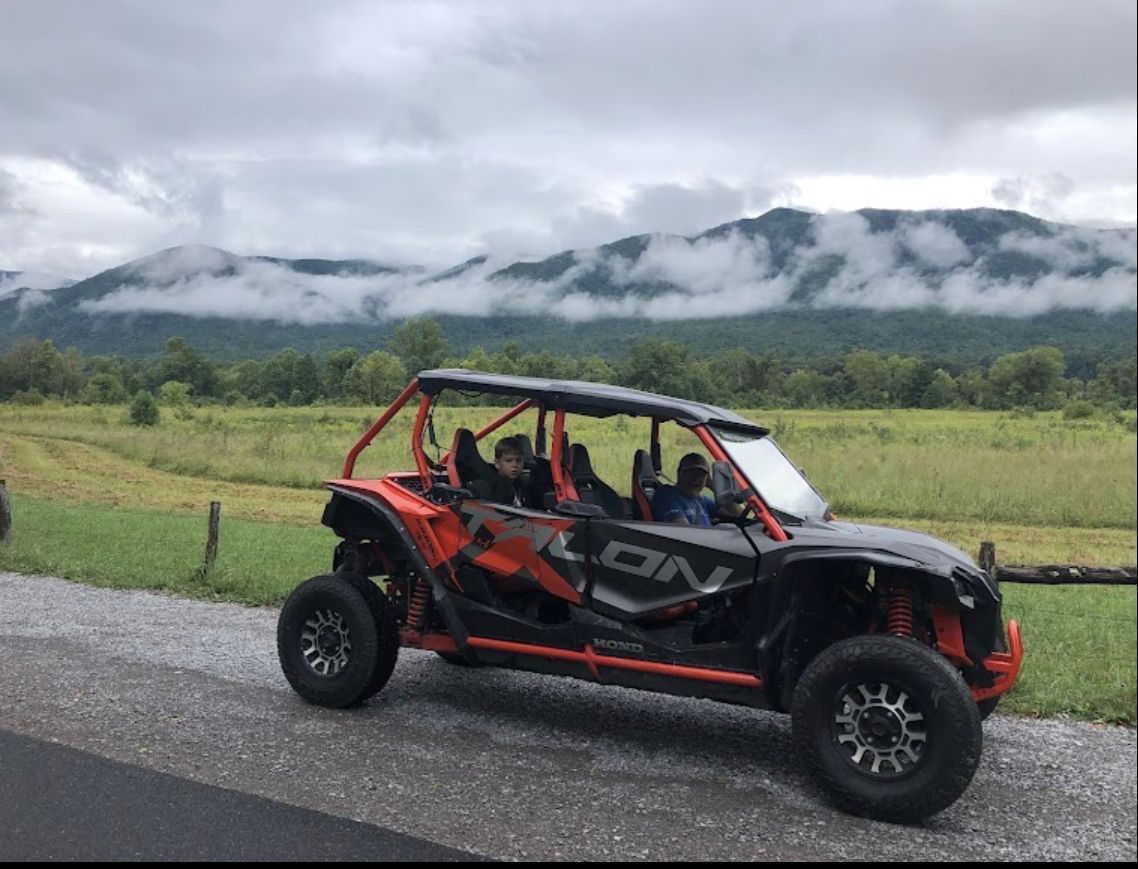 A atv is parked on the side of the road in front of a mountain.