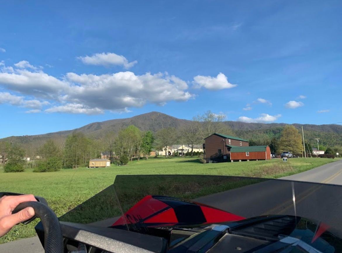 A person is driving a vehicle down a road with mountains in the background.