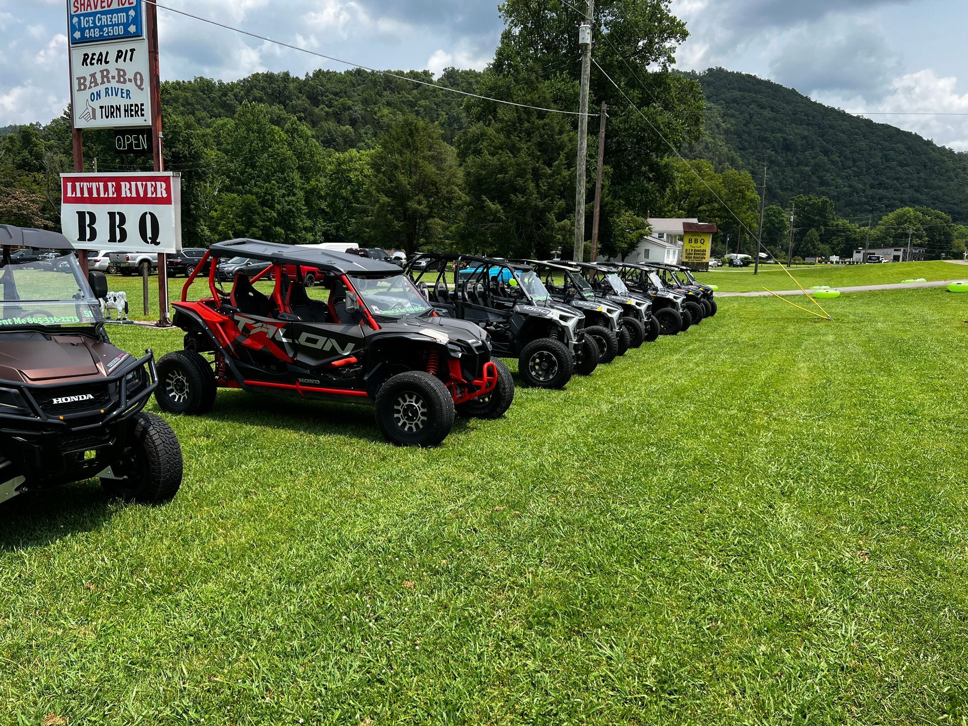 A row of atvs are parked in a grassy field.