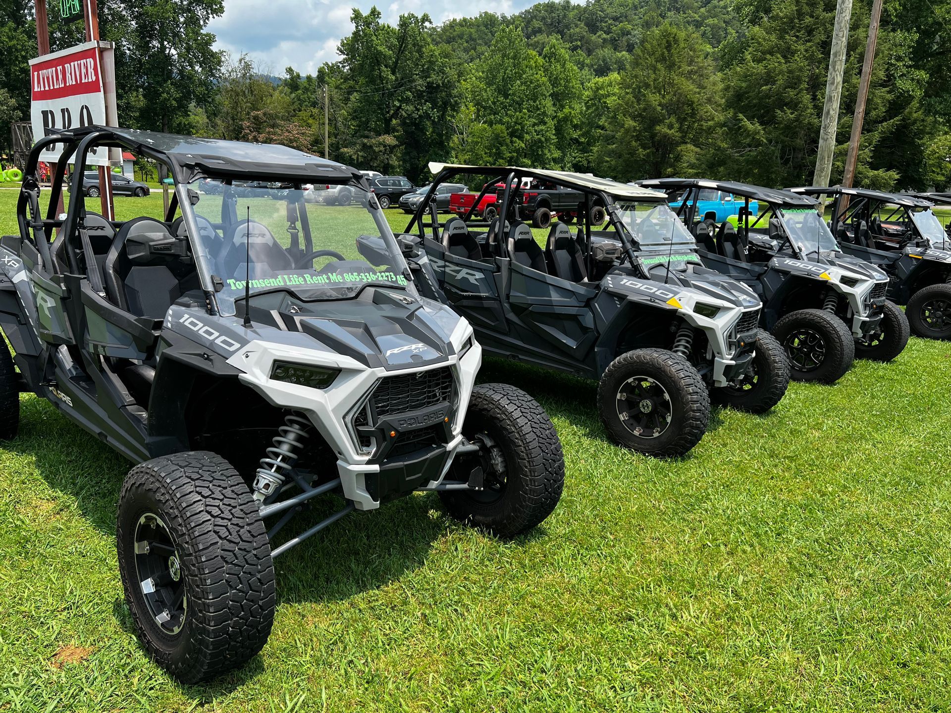 A row of atvs are parked in a grassy field.