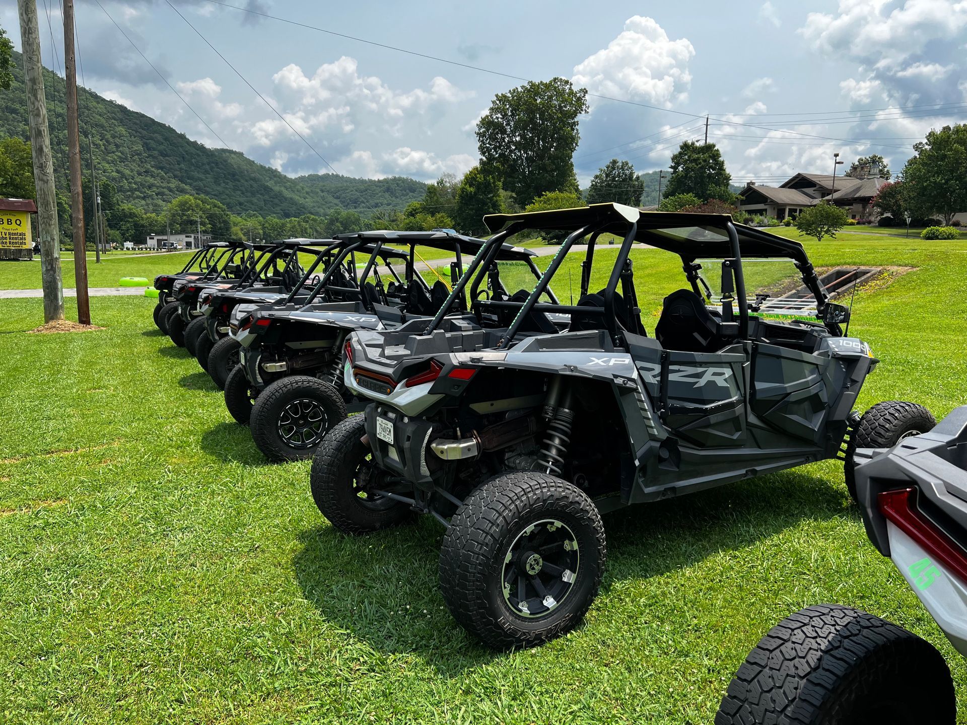 A row of atvs are parked in a grassy field.