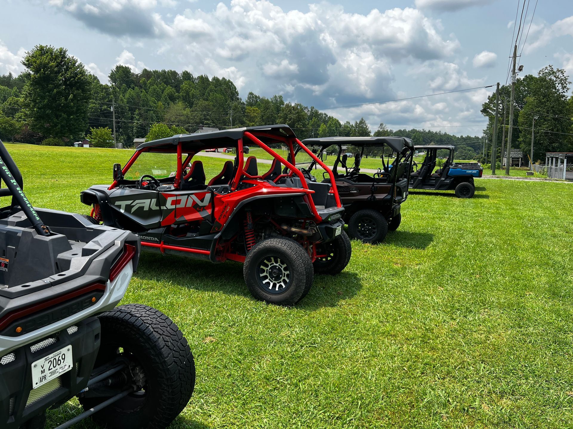 A row of atvs are parked in a grassy field.