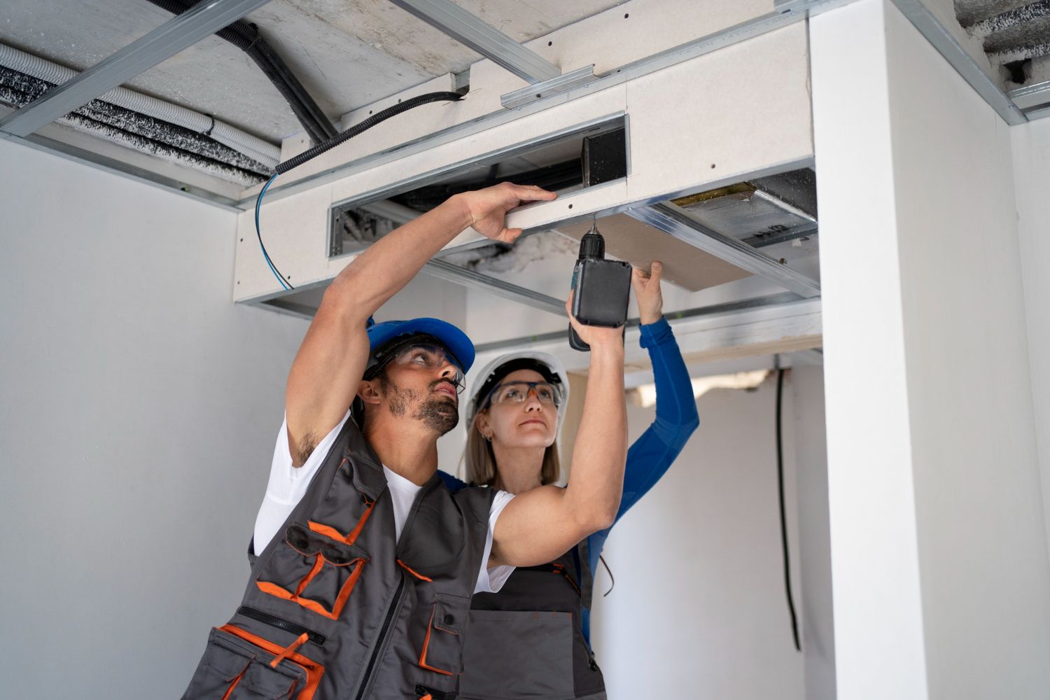 A man and a woman are working on a ceiling fan.