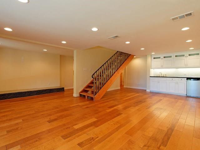 An empty room with hardwood floors and a staircase in a newly renovated home.
