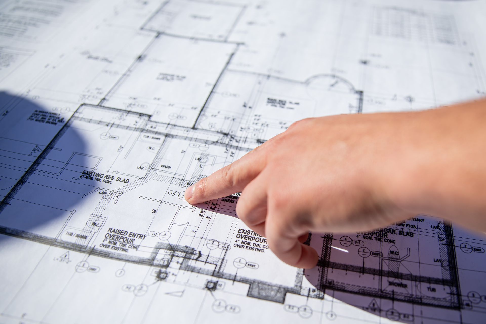 A person is pointing at a blueprint of a house.