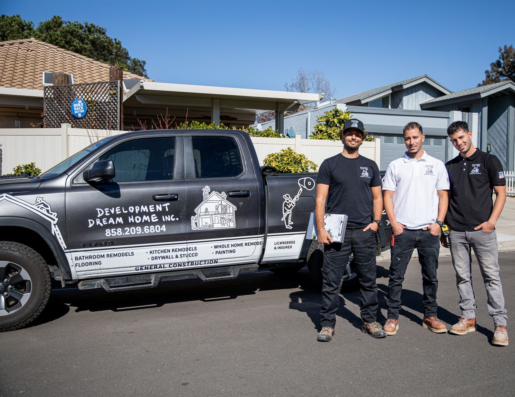 Three men are standing in front of a truck.