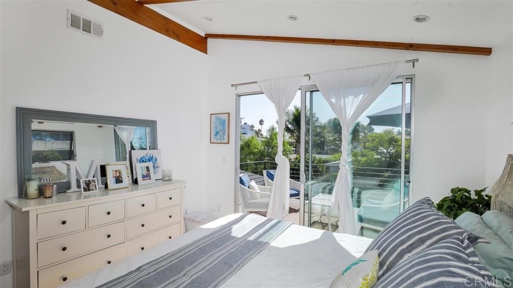 A bedroom with a large bed, dresser, mirror and sliding glass doors.