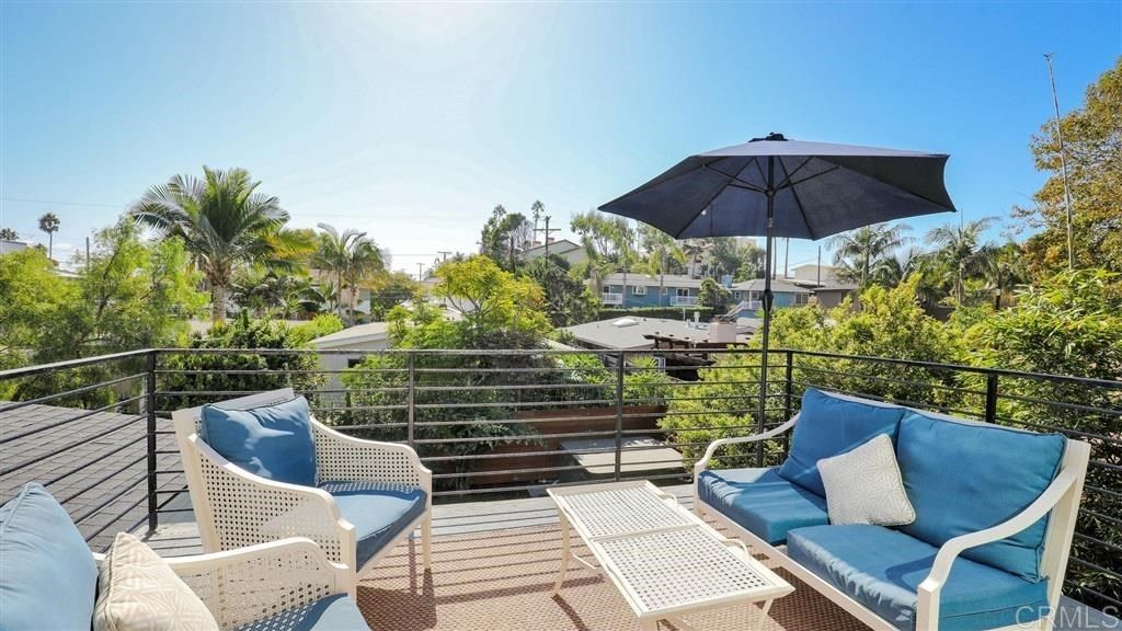A brand new and redesigned balcony with a couch, chairs, table and umbrella.