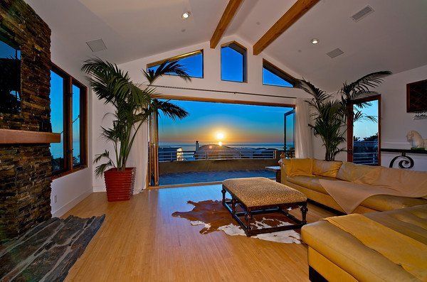 A living room with a couch and a fireplace and a view of the ocean in San Diego, California.