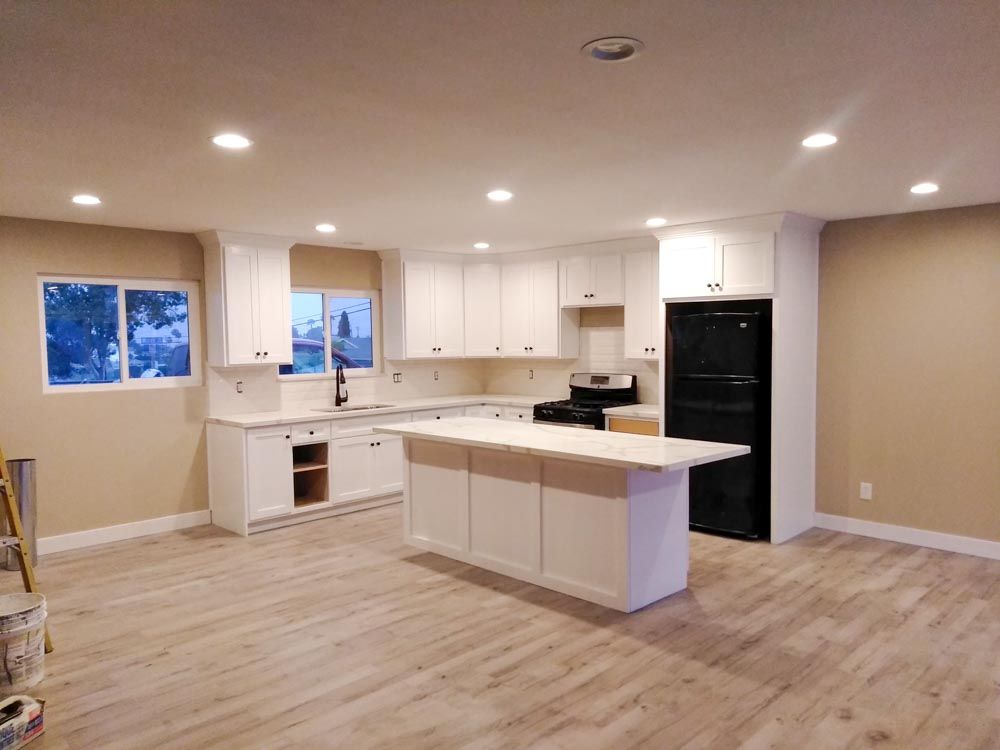 A kitchen with white cabinets and a large island in the middle.