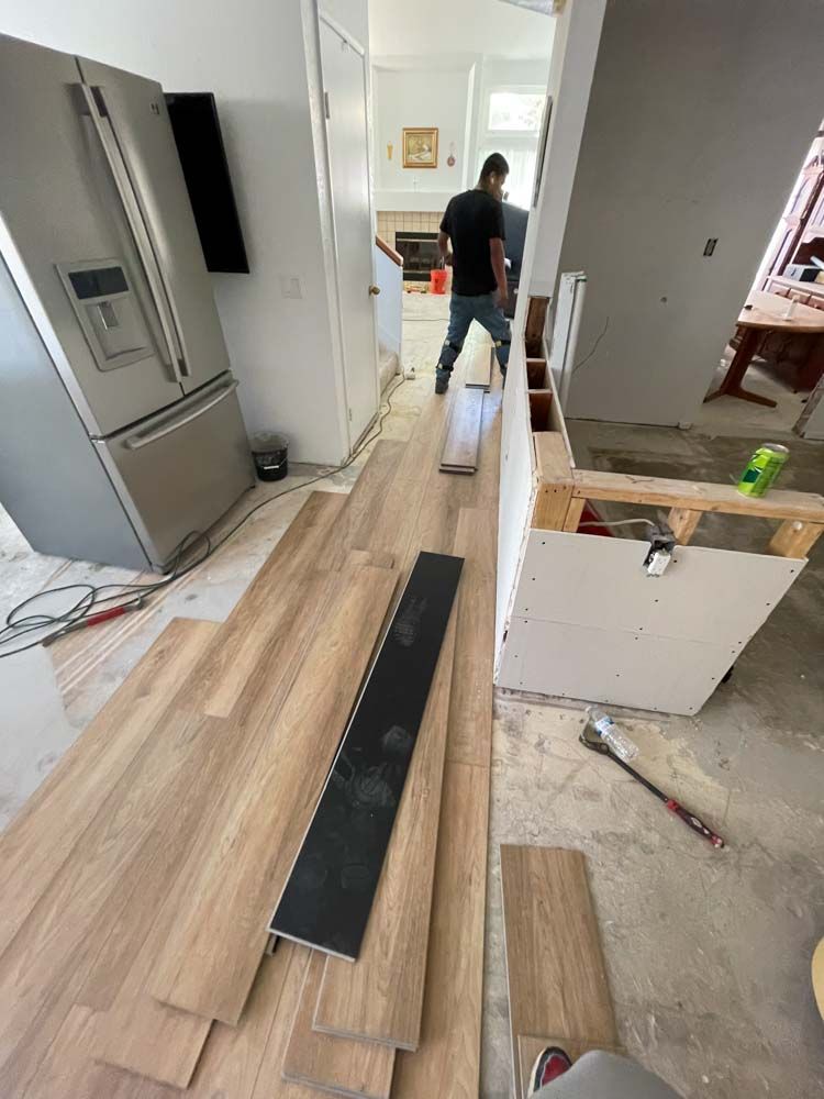 A man is installing a wooden floor in a kitchen.